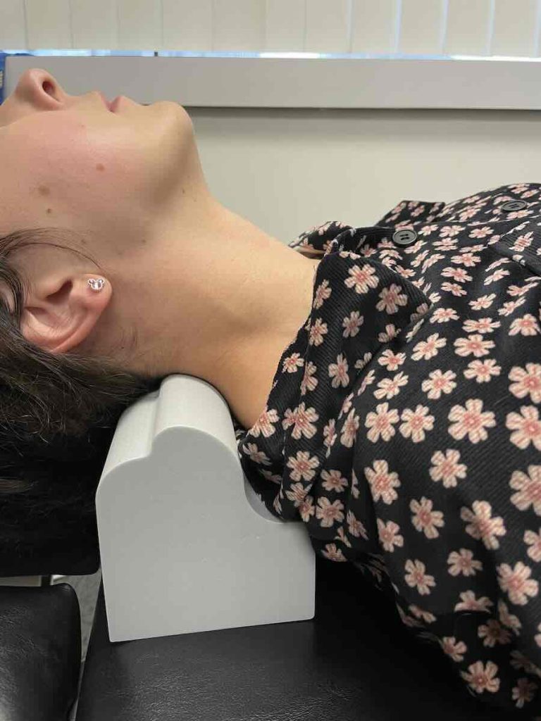 Demonstration of cervical spine traction using a chiropractic neck block denneroll