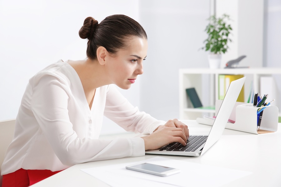 Woman sitting with forward head posture at a laptop
