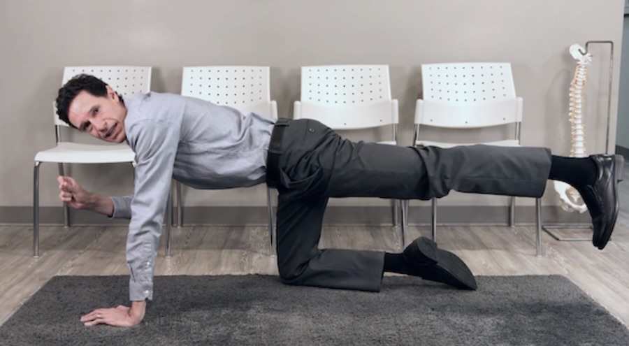 Chiropractor demonstrating the bird-dog exercise to improve core strength and low back stability.