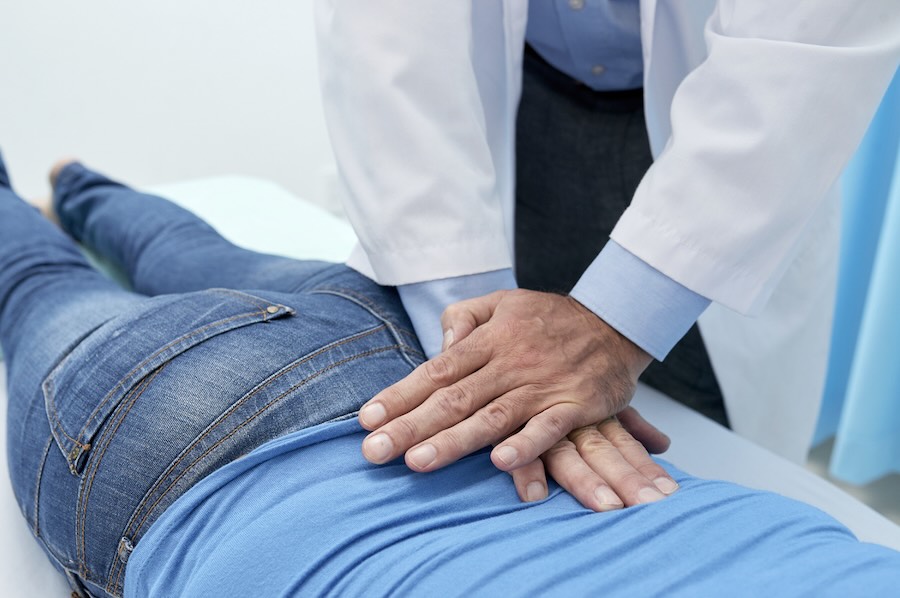 Chiropractor performing a gentle spinal adjustment on a patient’s lower back.