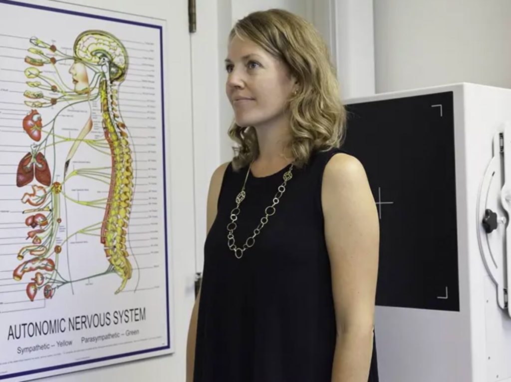 Chiropractor assessing posture alignment to identify imbalances affecting neck and back strain.