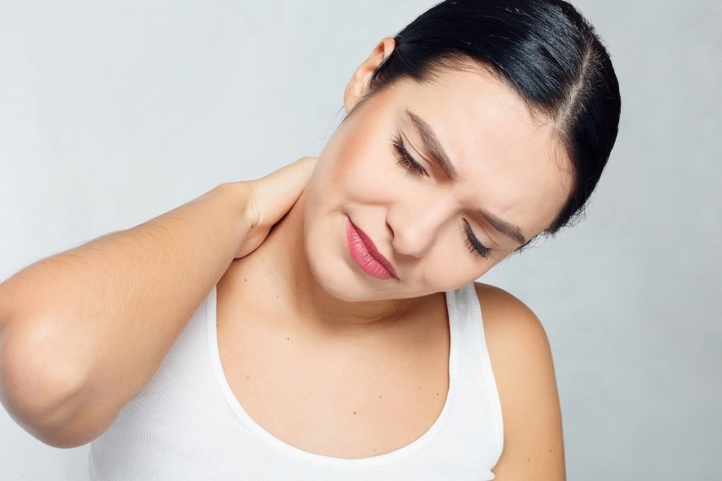 Person with mild neck pain holding the side of their neck