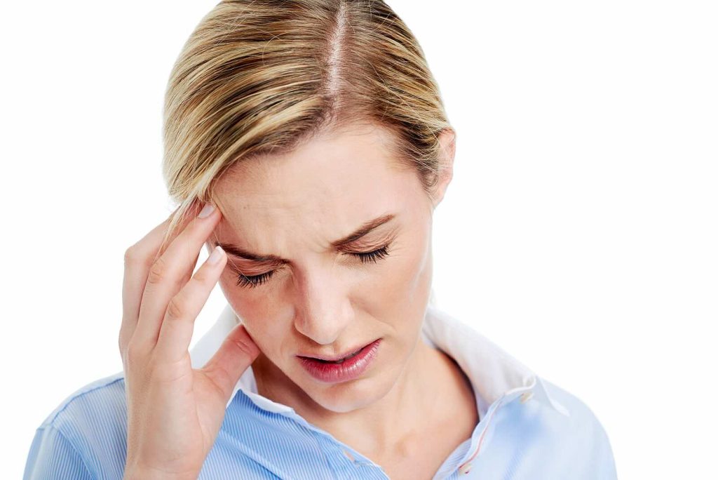 Woman touching her temple with headache related to neck tension.